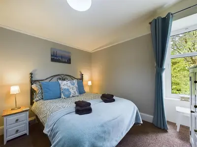 a bedroom with a bed with blue pillows and a window at The Tregortha B&B in Tighnabruaich