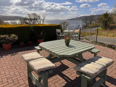 a picnic table and chairs with a view of the water at The Tregortha B&B in Tighnabruaich
