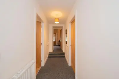 a hallway with white walls and a long corridor at The Lodge House Callander in Callander