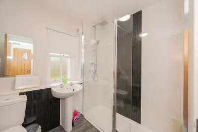 a white bathroom with a shower and a sink at The Lodge House Callander in Callander