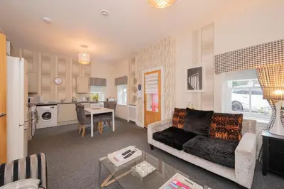 a living room with a couch and a kitchen at The Lodge House Callander in Callander