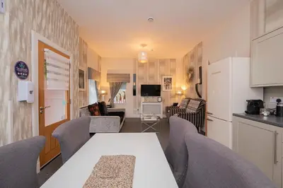 a kitchen and living room with a white table and chairs at The Lodge House Callander in Callander