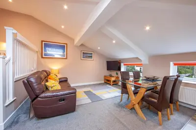 a living room with a leather couch and a table at Mandarin Premier Apartments B - Loft studio apt in Oban
