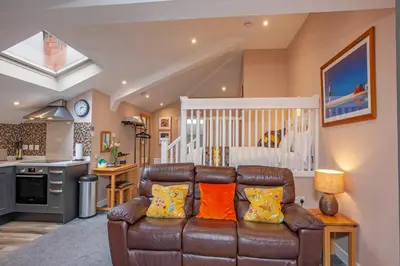 a living room with a leather couch and a baby crib at Mandarin Premier Apartments B - Loft studio apt in Oban