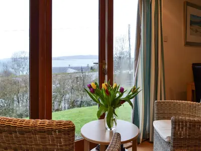 a vase of flowers on a table in front of a window at Tigh An Aighear in Arduaine