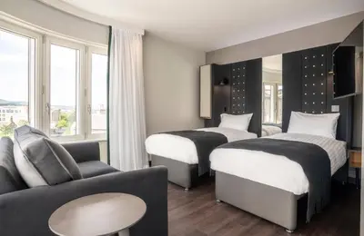 a hotel room with two beds and a couch at Point A Hotel Edinburgh Haymarket in Edinburgh
