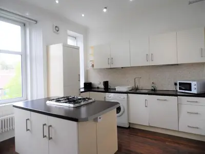a kitchen with white cabinets and a black counter top at 4 Bed Apartment, Paisley - Near GLA Airport in Paisley