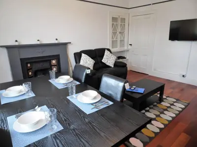 a living room with a table and a fireplace at 4 Bed Apartment, Paisley - Near GLA Airport in Paisley