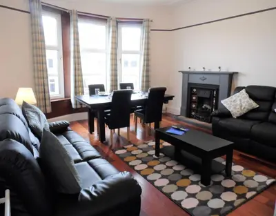 a living room with a couch and a table and chairs at 4 Bed Apartment, Paisley - Near GLA Airport in Paisley