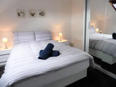 a white bed with two blue pillows on it at 4 Bed Apartment, Paisley - Near GLA Airport in Paisley
