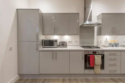 a white kitchen with white cabinets and a microwave at Haymarket Spacious 3 Bedroom Street Level in Edinburgh
