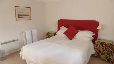 a bedroom with a white bed with a red headboard at Arndean Cottages in Dollar
