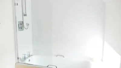 a white bathroom with a tub and a mirror at Arndean Cottages in Dollar