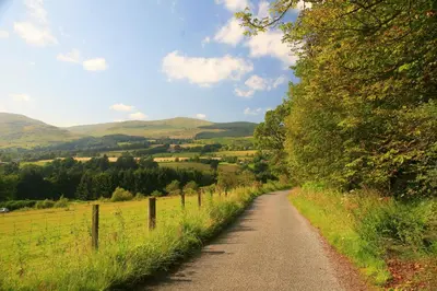 a dirt road in a field with a fence at Arndean Cottages in Dollar