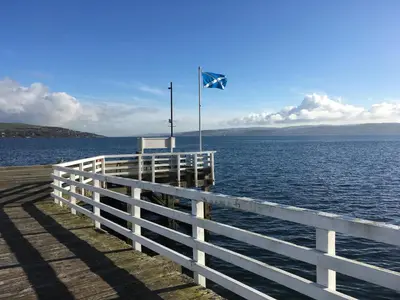 a pier with a flag on top of the water at Pier View in Dunoon