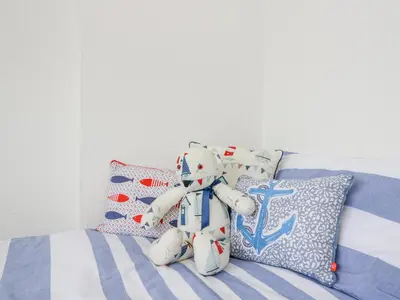a teddy bear sitting on a bed with pillows at Pier View in Dunoon