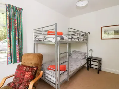 a bedroom with a bunk bed with a chair and a chair at Tower Lodge in Dalmally