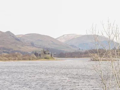 a castle on an island in the middle of a lake at Tower Lodge in Dalmally