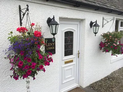 a white house with flowers and a sign on it at Leny Estate in Callander