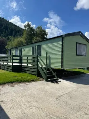 a green trailer with a fence and a house at Swift Bordeaux Sea View 15 in Dunoon