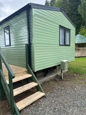 a green caravan with a stairs leading to it at The Manor Sea View 1A in Ardentinny