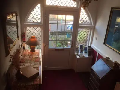 a hallway with a door and a lamp on a table at Haven House in Largs