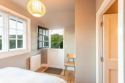 a bedroom with a bed and a window and a chair at Black Stair Room - En Suite in Helensburgh