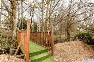 a wooden fence with green stairs in a garden at Grandeagles Extra large lodge in Auchterarder