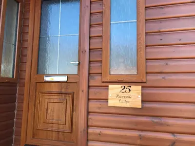 a wooden door on a house with a sign on it at Grandeagles Extra large lodge in Auchterarder