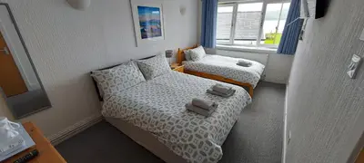 a small bedroom with two beds and a window at Cala Sith Guesthouse in Port Ellen