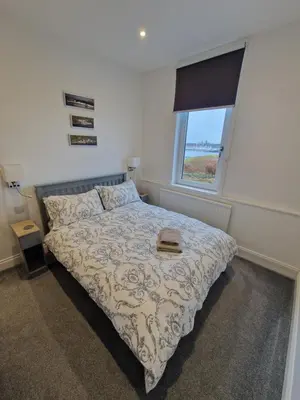 a bedroom with a bed and a window at Cala Sith Guesthouse in Port Ellen