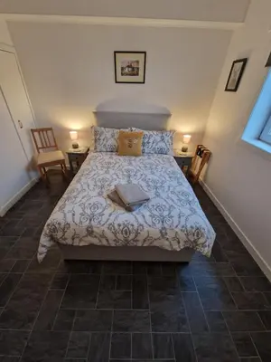a bedroom with a bed and two chairs at Cala Sith Guesthouse in Port Ellen