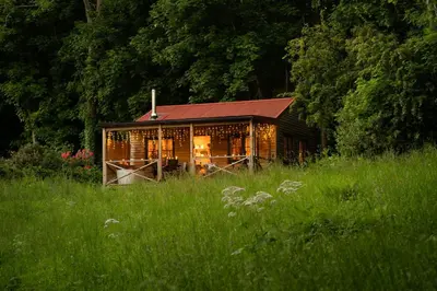 a house with a red roof in the middle of a field at Luxury Off-Grid Cabin with Outdoor Bath in Scotland in Clachan of Campsie