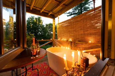 a bathroom with a tub and candles on a balcony at Luxury Off-Grid Cabin with Outdoor Bath in Scotland in Clachan of Campsie