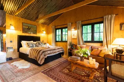a bedroom with a bed and a couch in a room at Luxury Off-Grid Cabin with Outdoor Bath in Scotland in Clachan of Campsie