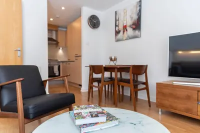 a living room with a chair and a table and a tv at Modern 2 bed BroomPark/Central apt. with Parking in Glasgow