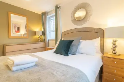 a bedroom with a large white bed and a mirror at Merchant City Glasgow Green Apartment With Parking in Glasgow