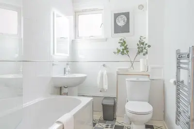 a white bathroom with a tub and a toilet and a sink at Merchant City Glasgow Green Apartment With Parking in Glasgow