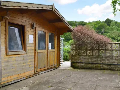 a wooden cabin with a door and a balcony at Carribber Beech in Torphichen