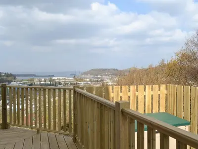 a wooden deck with a table and a fence at Sealladh Alainn in Oban