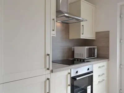 a kitchen with white cabinets and a microwave at Sealladh Alainn in Oban