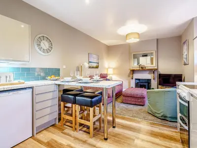 a kitchen with a table and a living room at Ivy Cottage in Dunoon