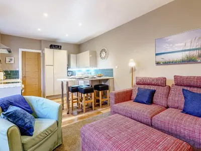 a living room with a couch and a kitchen at Ivy Cottage in Dunoon