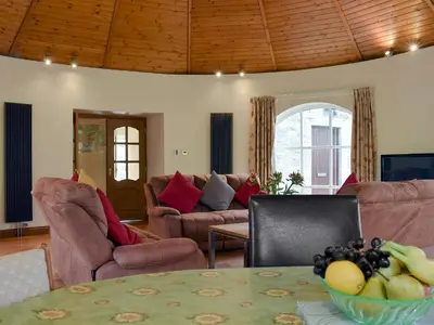 a living room with couches and a table with a bowl of fruit at Horsemill - Uk10794 in Ballingry