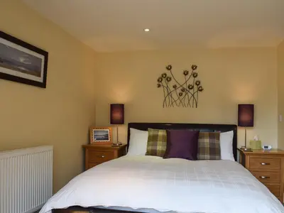 a bedroom with a white bed with two night stands at Lochearnside Lodge in Saint Fillans