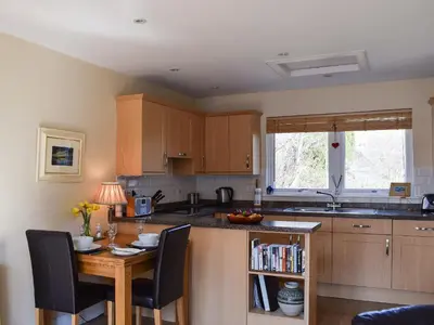 a kitchen with a table with chairs and a counter top at Lochearnside Lodge in Saint Fillans