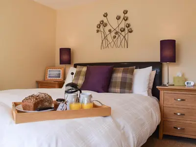 a bedroom with a bed with a tray of food on it at Lochearnside Lodge in Saint Fillans