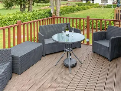 a patio with two chairs and a table with wine glasses at Bridge End Lodge in Dollar