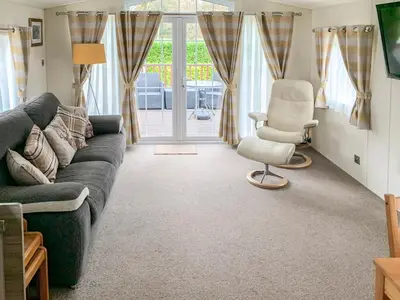 a living room with a couch and a chair and a window at Bridge End Lodge in Dollar