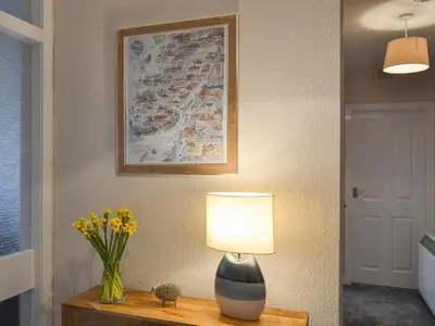 a lamp on a table with a vase of flowers at Finlaggan Apartment in Oban
